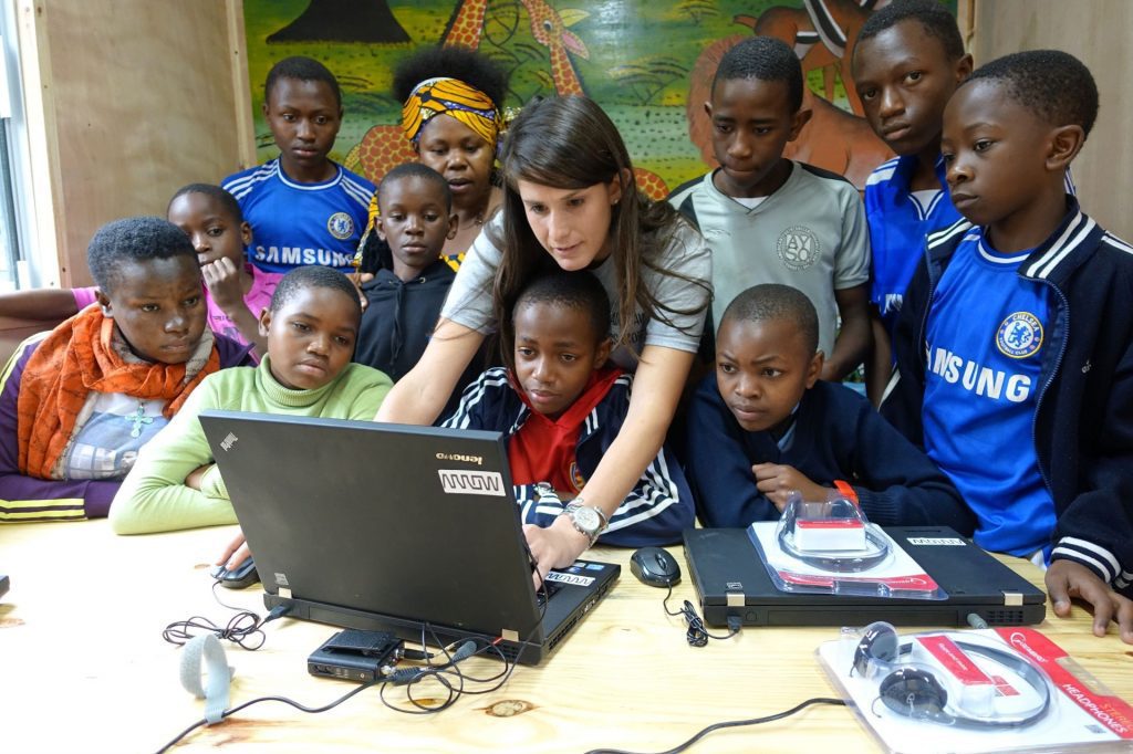 Woman explaining something to kids in a computer.