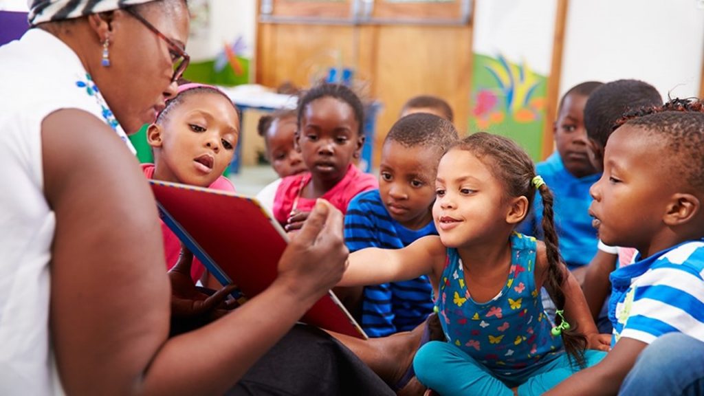 Teacher showing book to kids.