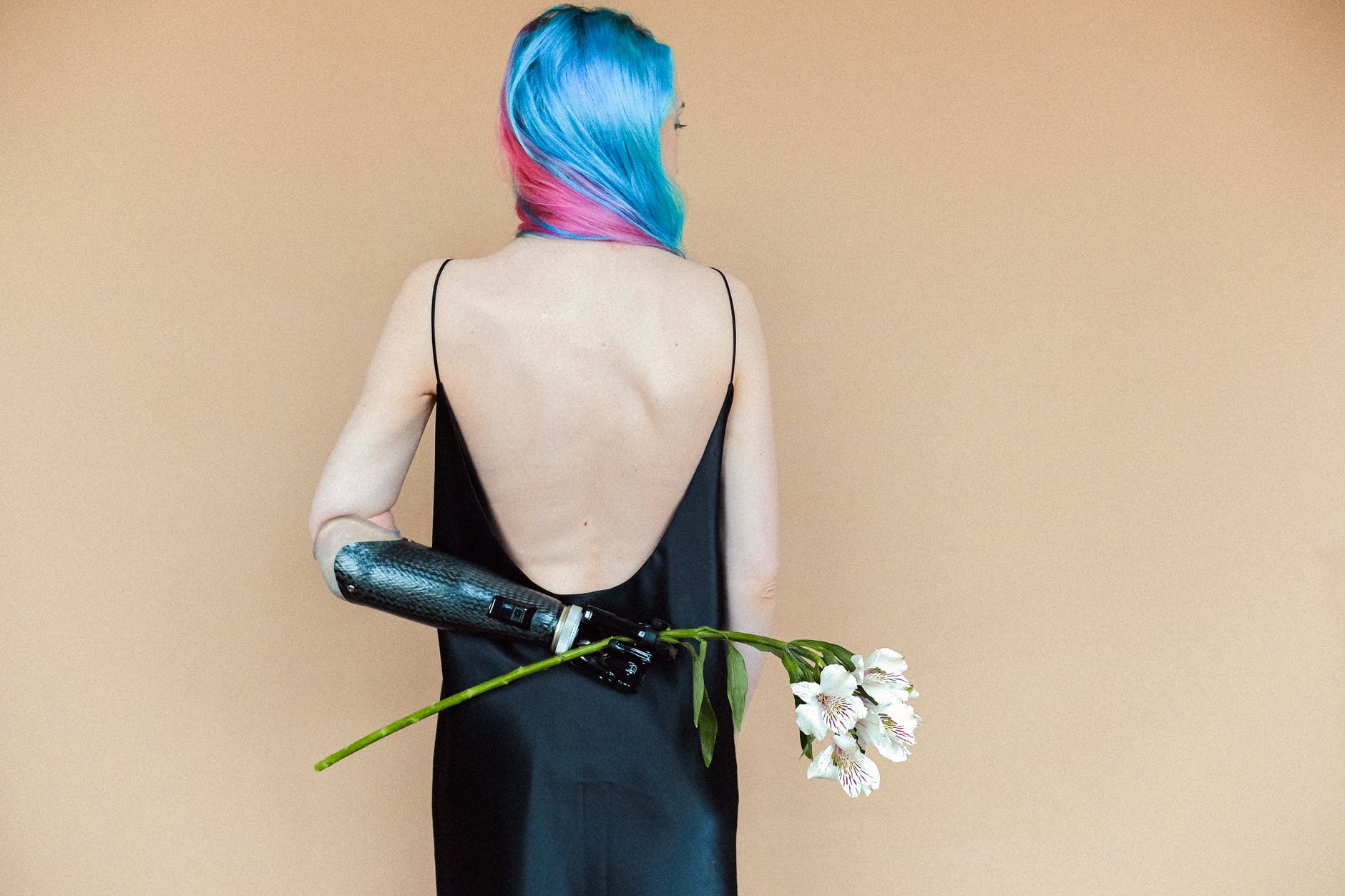 woman in black spaghetti strap dress holding white flowers